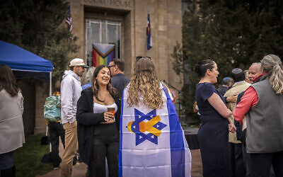 An attendee drapes herself in an Israeli flag during a community gathering at the site of an antisemitic firebombing attack against people holding a demonstration for kidnapped Israeli citizens in Gaza in Boulder, Colorado, on June 4, 2025. (Photo by Chet Strange / AFP)
