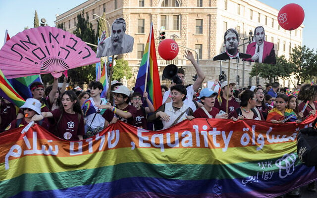 Participants hoist cut-outs of anti-LGBTQ Israeli politicians and a giant pride flag with the words 'equality' and 'peace' in Hebrew, English and Arabic as they march through Jerusalem's city center during the capital's annual Pride Parade, on June 5, 2025. (AHMAD GHARABLI / AFP)
