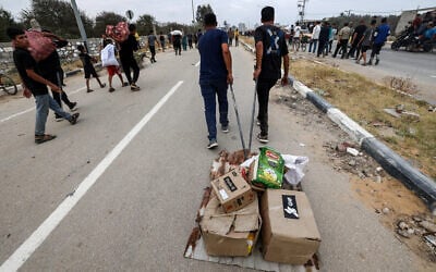 People carry relief supplies from the Gaza Humanitarian Foundation (GHF), a private US-backed aid group, as displaced Palestinians return from an aid distribution center in the central Gaza Strip, June 8, 2025. (Eyad BABA / AFP)
