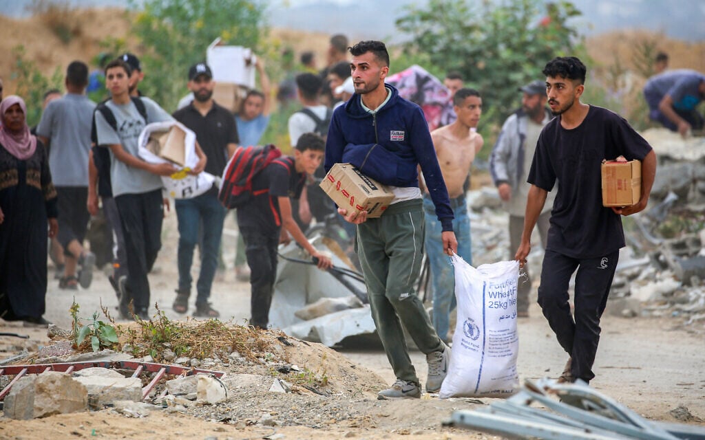 People carry relief supplies from the Gaza Humanitarian Foundation (GHF), a private US-backed aid group that has bypassed the longstanding UN-led system in the territory, as displaced Palestinians return from an aid distribution center in the central Gaza Strip on June 8, 2025. (Eyad BABA / AFP)