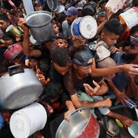 Palestinians wait for food at a distribution point in Nuseirat, in the central Gaza Strip, on June 11, 2025. (Eyad BABA / AFP)