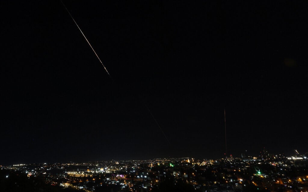 Debris of a missile fired from Iran toward Israel leaves a trail in the night sky over Jerusalem after being intercepted on June 13, 2025. (AHMAD GHARABLI / AFP)
