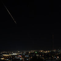 Debris of a missile fired from Iran toward Israel leaves a trail in the night sky over Jerusalem after being intercepted on June 13, 2025. (AHMAD GHARABLI / AFP)