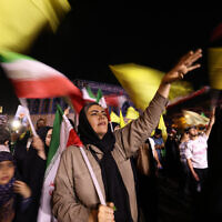 Iranians wave flags as they celebrate in the streets of Tehran after missile attack that hit Tel Aviv on June 13, 2025.  (Photo by Atta KENARE / AFP)