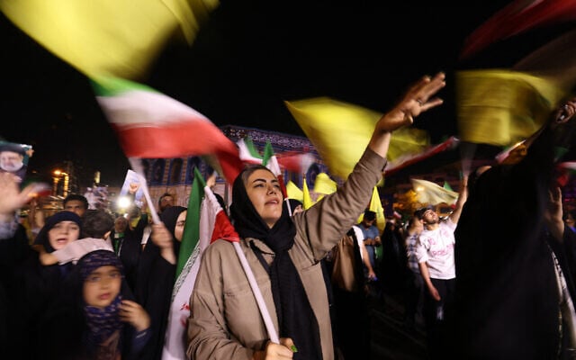 Iranians wave flags as they celebrate in the streets of Tehran after missile attack that hit Tel Aviv on June 13, 2025.  (Photo by Atta KENARE / AFP)