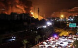 Vehicles jam a highway as a fire blazes nearby in the oil depots of Shahran, northwest of Tehran, on June 15, 2025. (ATTA KENARE / AFP)