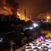 Vehicles jam a highway as a fire blazes nearby in the oil depots of Shahran, northwest of Tehran, on June 15, 2025. (ATTA KENARE / AFP)