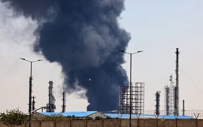 A plume of heavy smoke and fire rise over an oil refinery in southern Tehran, after it was hit in an overnight Israeli strike, on June 15, 2025. (Photo by ATTA KENARE / AFP)