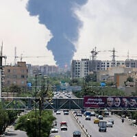 Portraits of Iranian military generals and nuclear scientists, killed in Israel's June 13 attack are displayed above a road, as a plume of heavy smoke and fire rise from an oil refinery in southern Tehran, after it was hit in an overnight Israeli strike, on June 15, 2025. (ATTA KENARE / AFP)