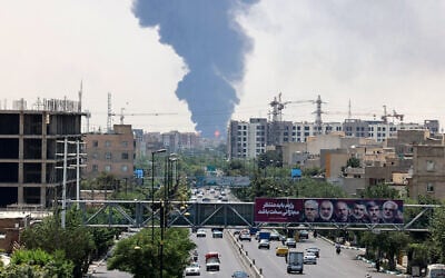 Portraits of Iranian military generals and nuclear scientists, killed in Israel's June 13 attack are displayed above a road, as a plume of heavy smoke and fire rise from an oil refinery in southern Tehran, after it was hit in an overnight Israeli strike, on June 15, 2025. (ATTA KENARE / AFP)