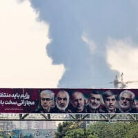 Portraits of Iranian military generals and nuclear scientists, killed in Israel's June 13 attack are displayed above a road, as a plume of heavy smoke rises from an oil refinery in southern Tehran, after it was hit in an overnight Israeli strike, on June 15, 2025. (ATTA KENARE / AFP)