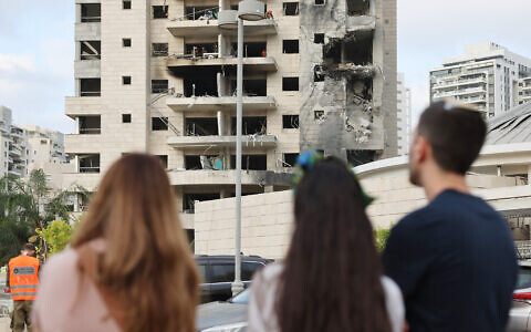 People look at a damaged building following a strike by an Iranian missile in the Israeli city of Petah Tikva on June 16, 2025. (Jack GUEZ / AFP)