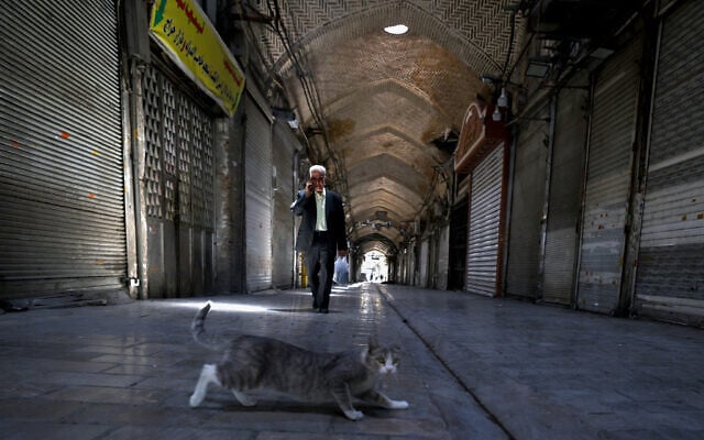 People walk past closed shops in Tehran's Grand Bazaar as fighting between Israel and Iran entered a fourth day on June 16, 2025. (Photo by ATTA KENARE / AFP)
