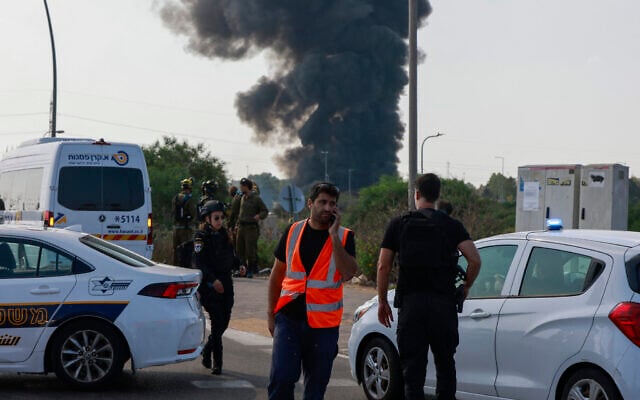 Israeli emergency services and police deploy on a closed-off road as smoke billows from a site near Tel Aviv following a barrage of Iranian rockets on June 17, 2025. (Menahem KAHANA / AFP)