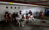 People take shelter in a parking lot in Tel Aviv amid a fresh barrage of Iranian rockets on June 17, 2025. (Menahem Kahana / AFP)