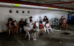 People take shelter in a parking lot in Tel Aviv amid a fresh barrage of Iranian rockets on June 17, 2025. (Menahem Kahana / AFP)