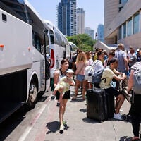 People arrive with their luggage before the departure of a bus slated to evacuate foreign passport holders, mainly Europeans, out of Israel, at a meeting point in Tel Aviv on June 17, 2025. The operation, coordinated by the Polish embassy, aims to evacuate several hundred people who will board buses headed to Sinai in Egypt, and from there continue to Warsaw, Poland. (Photo by Menahem Kahana / AFP)