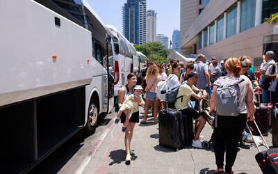 People arrive with their luggage before the departure of a bus slated to evacuate foreign passport holders, mainly Europeans, out of Israel, at a meeting point in Tel Aviv on June 17, 2025. The operation, coordinated by the Polish embassy, aims to evacuate several hundred people who will board buses headed to Sinai in Egypt, and from there continue to Warsaw, Poland. (Photo by Menahem Kahana / AFP)
