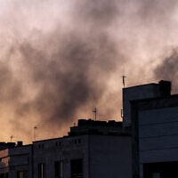 People stand on a rooftop as smoke billows following an Israeli strike in Tehran on June 17, 2025. (Atta Kenare/AFP)
