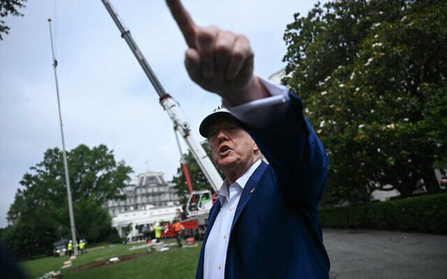 US President Donald Trump speaks to the press as workers install a large flag pole on the South Lawn of the White House in Washington, DC on June 18, 2025. (Brendan Smialowskyi/AFP)