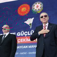 This handout photograph taken and released by Turkish Presidency Press Office on June 19, 2025, shows Turkey's President Recep Tayyip Erdogan (R) and Azerbaijan's President Ilham Aliyev (L) greeting supporters during the ceremony of the 250 thousand's post-quake houses in Kahramanmaras. (Photo by Handout / Turkish Presidency Press Office / AFP)