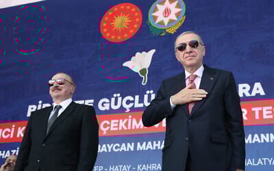 This handout photograph taken and released by Turkish Presidency Press Office on June 19, 2025, shows Turkey's President Recep Tayyip Erdogan (R) and Azerbaijan's President Ilham Aliyev (L) greeting supporters during the ceremony of the 250 thousand's post-quake houses in Kahramanmaras. (Photo by Handout / Turkish Presidency Press Office / AFP)
