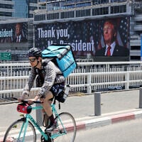 A man rides on a bridge in front of banners bearing a pictures of US President Donald Trump accompanied by a message thanking him, in Tel Aviv on June 22, 2025.  (Photo by AHMAD GHARABLI / AFP)