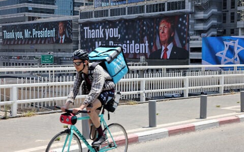 A man rides on a bridge in front of banners bearing a pictures of US President Donald Trump accompanied by a message thanking him, in Tel Aviv on June 22, 2025.  (Photo by AHMAD GHARABLI / AFP)