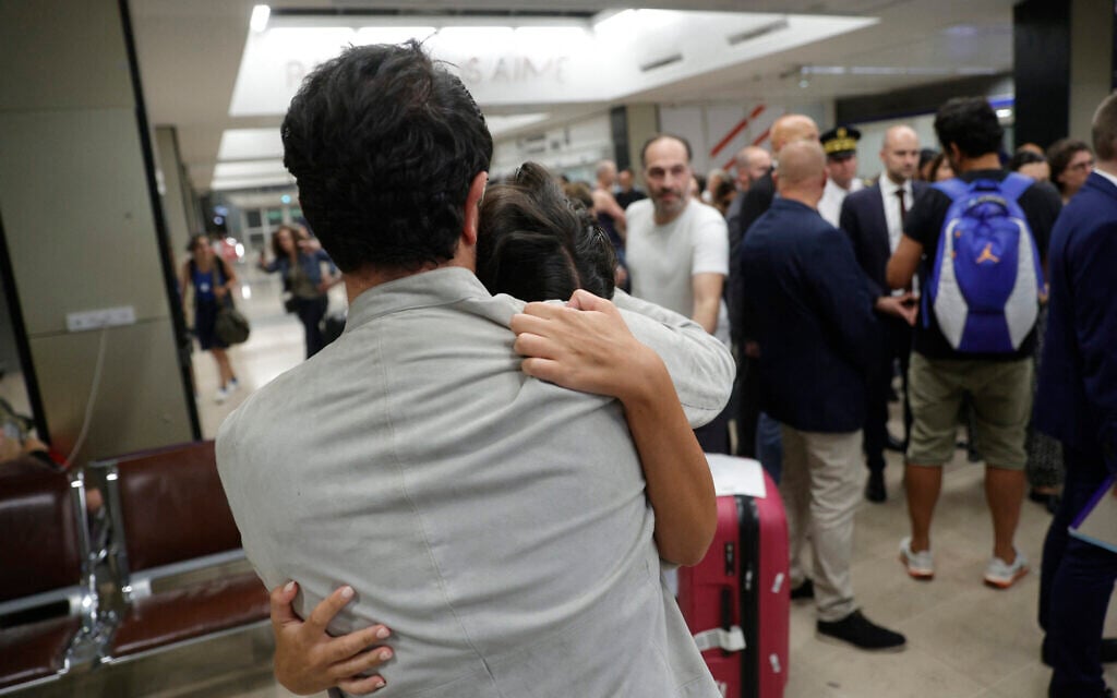 People hug as they are welcomed after arriving at Paris-Orly airport, in Orly, south of Paris, early on June 23, 2025, after taking a repatriation flight of French nationals leaving Israel via Amman (GEOFFROY VAN DER HASSELT / AFP)