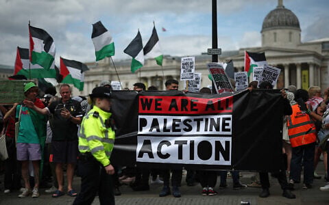 Police officers monitor protesters holding a banner during a protest in support of anti-Israel, pro-Palestinian group Palestine Action, in Trafalgar Square, central London, on June 23, 2025. (Henry Nicholls / AFP)