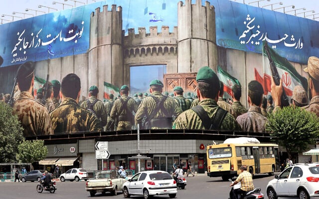 Vehicles drive past an anti-Israeli banner depicting Iranian soldiers heading to attack Israeli territory on Enghelab (Revolution) Square, in Tehran on June 24, 2025 (ATTA KENARE / AFP)