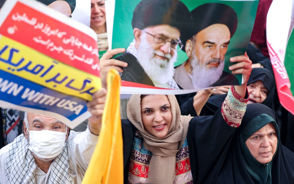 An Iranian woman holds a poster with portraits of Iranian supreme leader Ayatollah Ali Khamenei (L) and late supreme leader Ayatollah Ruhollah Khomeini as people celebrate a ceasefire between Iran and Israel at Enghlab Square in the capital Tehran on June 24, 2025. (Photo by ATTA KENARE / AFP)