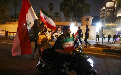 People riding on a moped wave Iraqi and Iranian flags as they celebrate in front of the Iranian embassy in Baghdad on June 24, 2025, following a ceasefire between Israel and Iran. (AHMAD AL-RUBAYE / AFP)