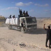 Gunmen are seen on trucks carrying aid after they entered the northern Gaza Strip from Israel, west of Beit Lahia on June 25, 2025. (Bashar Taleb/AFP)