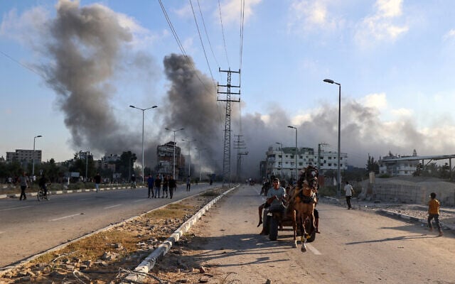 Smoke plumes rise during an Israeli strike as Palestinians riding a horse-pulled cart speed along the Salah al-Din road near the Nusseirat refugee camp in the central Gaza Strip, on June 25, 2025. (Eyad BABA / AFP) Smoke plumes rise during an Israeli strike as Palestinians riding a horse-pulled cart speed along the Salah al-Din road near the Nusseirat refugee camp in the central Gaza Strip, on June 25, 2025. (Eyad BABA / AFP)