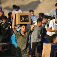 Palestinians pick up food parcels from a distribution point set up by the Gaza Humanitarian Foundation (GHF), on June 25, 2025. (Eyad BABA / AFP)