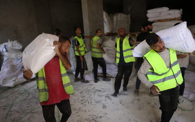 Volunteers carry bags of flour to be distributed to Palestinians at a depot set up by the independent Save Youth Future Society (SYFS), in coordination with the UN World Food Programme (WFP), in Gaza City on June 26, 2025. (BASHAR TALEB / AFP)