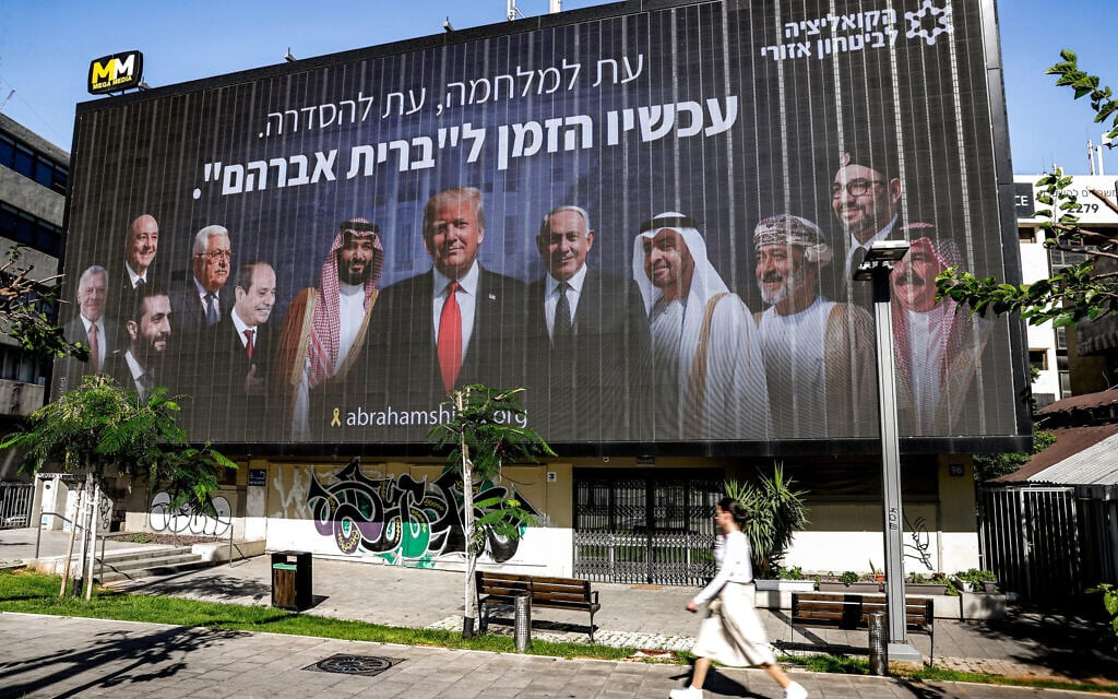 A woman walks past a billboard displayed in Tel Aviv on June 26, 2025 by the Coalition for Regional Security showing Arab leaders surrounding US President Donald Trump and Prime Minister Benjamin Netanyahu, with a slogan reading "Now is the time for the Abraham Accords." (Jack GUEZ / AFP)