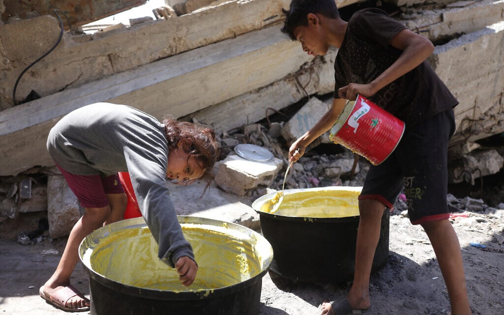 Palestinian children scrape the pot for a portion of food at a food distribution point in Gaza City on June 27, 2025. (Bashar Taleb/AFP)