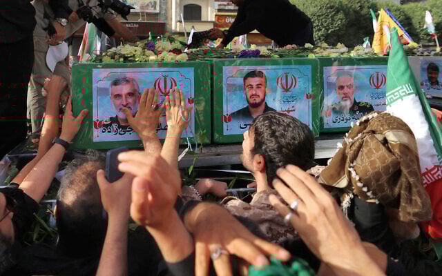 Mourners stand next to the coffin of Iranian Revolutionary Guards commander Amir ali Hjizadeh (L), and other military commanders killed during Israeli strikes on the first day of the war, during their funeral procession at Enqelab Square in the capital Tehran on June 28, 2025 (ATTA KENARE / AFP)