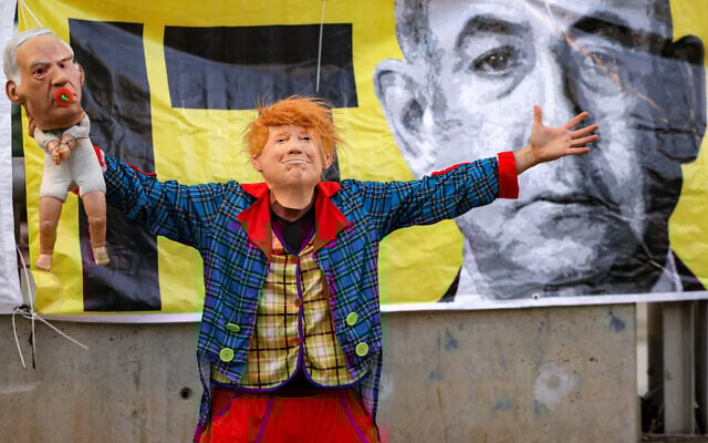 A demonstrator in a clown costume with a mask depicting US President Donald Trump holds a baby puppet depicting Prime Minister Benjamin Netanyahu during an anti-government protest calling for action to secure the release of Israeli hostages held captive in the Gaza Strip by Palestinian militants since the 2023 October 7 attacks, in Tel Aviv on June 28, 2025. (Jack GUEZ / AFP) A demonstrator in a clown costume with a mask depicting US President Donald Trump holds a baby puppet depicting Prime Minister Benjamin Netanyahu during an anti-government protest calling for action to secure the release of Israeli hostages held captive in the Gaza Strip by Palestinian militants since the 2023 October 7 attacks, in Tel Aviv on June 28, 2025. (Jack GUEZ / AFP)