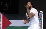 To the backdrop of a Palestinian flag, Bobby Vylan of British duo Bob Vylan performs on the West Holts Stage on the fourth day of the Glastonbury festival at Worthy Farm in the village of Pilton in Somerset, southwest England, on June 28, 2025. (Oli SCARFF / AFP)
