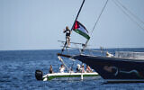 Activist Greta Thunberg stands near a Palestinian flag after boarding the Madleen boat and before setting sail for Gaza along with activists of the Freedom Flotilla Coalition, departing from the Sicilian port of Catania, Italy on June 1, 2025. (AP Photo/Salvatore Cavalli)