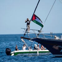 Activist Greta Thunberg stands near a Palestinian flag after boarding the Madleen boat and before setting sail for Gaza along with activists of the Freedom Flotilla Coalition, departing from the Sicilian port of Catania, Italy on June 1, 2025. (AP Photo/Salvatore Cavalli)