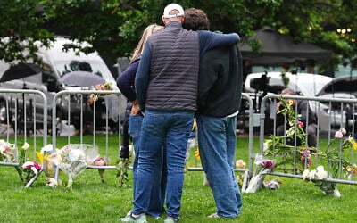 As Jennifer Dechtman, back, looks on, her husband Evan, front left, consoles his son, Isaac, right, at a makeshift memorial for victims of an attack outside of the Boulder County, Colorado, courthouse Tuesday, June 3, 2025, in Boulder, Colorado. (AP Photo/David Zalubowski)