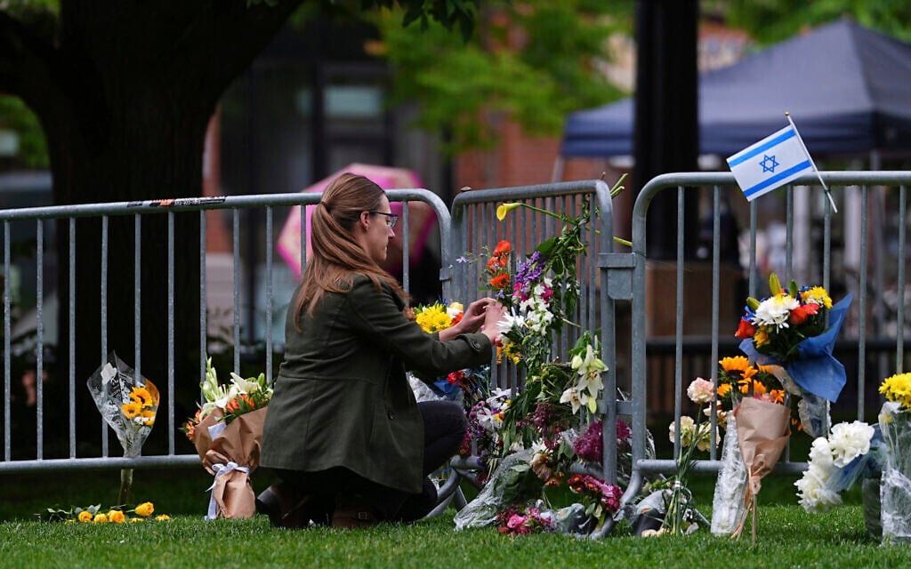 A woman places a bouquet of flowers at a makeshift memorial for victims of an antisemitic firebombing attack against demonstrators calling attention to the hostages being held by Hamas in Gaza, outside of the Boulder County, Colorado, courthouse, June 3, 2025. (AP Photo/David Zalubowski)