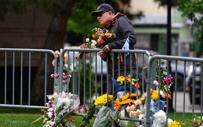 A man affixes a bouquet of flowers to a makeshift memorial for victims of an attack outside of the Boulder County courthouse, June 3, 2025, in Boulder, Colorado. (AP Photo/David Zalubowski)