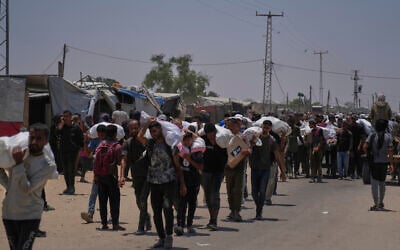 Palestinians carry bags containing food and humanitarian aid packages delivered by the Gaza Humanitarian Foundation, in Rafah, southern Gaza, June 9, 2025. (AP/Abdel Kareem Hana)