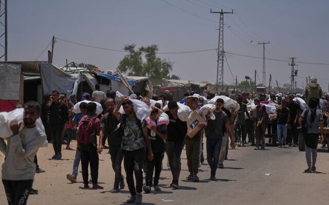 Palestinians carry bags containing food and humanitarian aid packages delivered by the Gaza Humanitarian Foundation, in Rafah, southern Gaza, June 9, 2025. (AP/Abdel Kareem Hana)