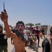 A Palestinian waves a knife and shouts to the camera in Arabic, 'We get food with the taste of death and blood,' as he carries a bag containing food and humanitarian aid packages delivered by the US- and Israel-backed Gaza Humanitarian Foundation in Rafah, southern Gaza Strip, June 10, 2025. (AP Photo/Abdel Kareem Hana)